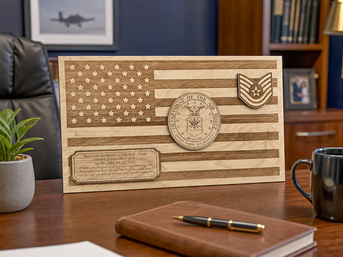 A personalized wooden plaque featuring an engraved American flag design, a circular military emblem, and a chevron insignia, displayed on a wooden desk in an office setting.